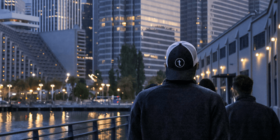 Two individuals overlooking a waterfront cityscape at dusk